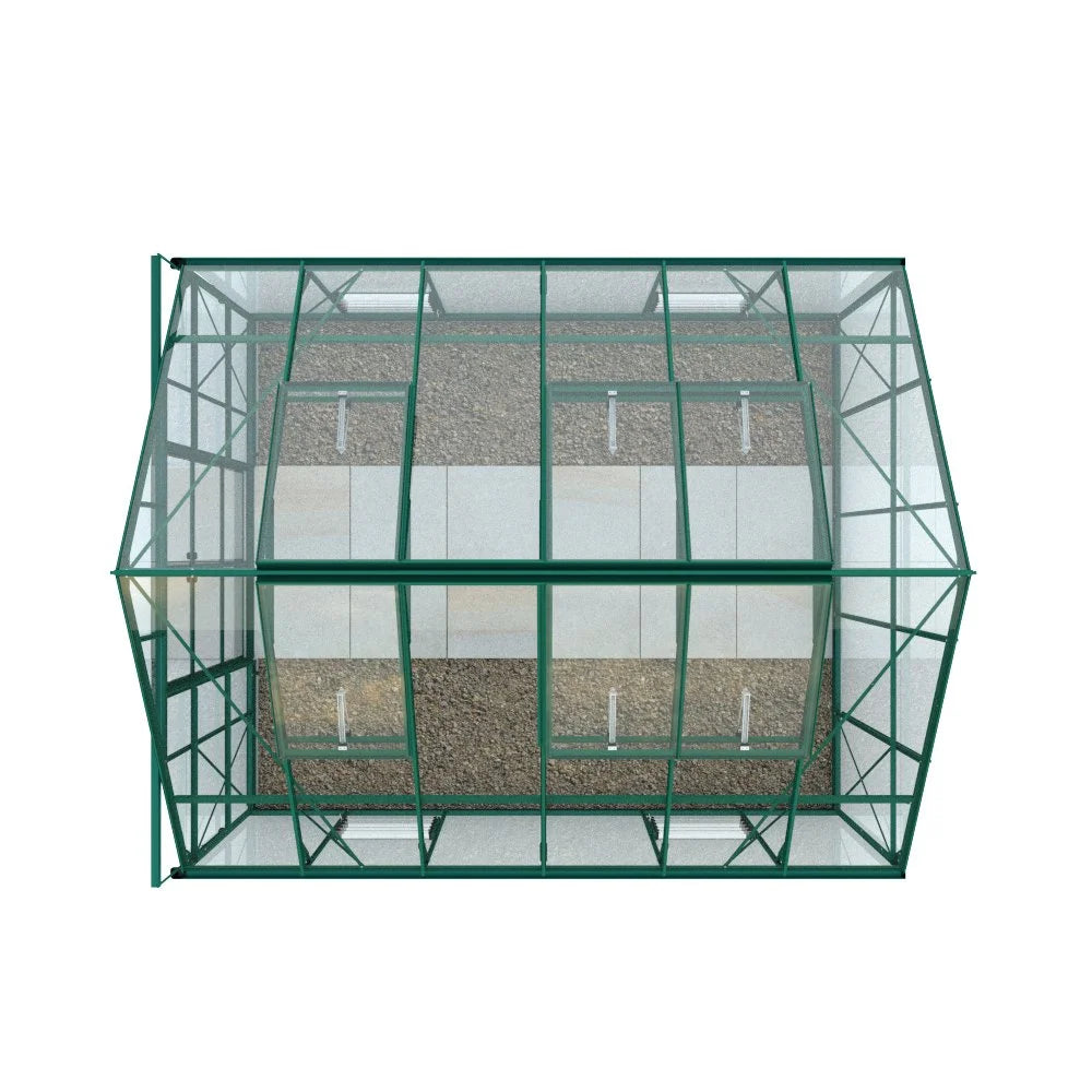 A rectangular Rhino Greenhouse with a green metal frame and glass panels. It stands on a gravel surface with larger stone slabs arranged in a path inside.