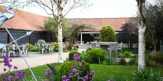 A converted outbuilding in a landcaped courtyard with tables and chairs