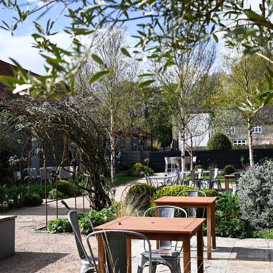 A converted outbuilding in a landcaped courtyard with tables and chairs