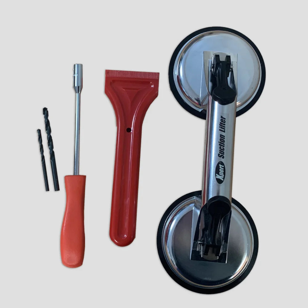 Tools for Rhino Greenhouse installation: two drill bits, a screwdriver, a red scraper, and a metal suction lifter labeled Neta Suction Lifter arranged on a plain surface.